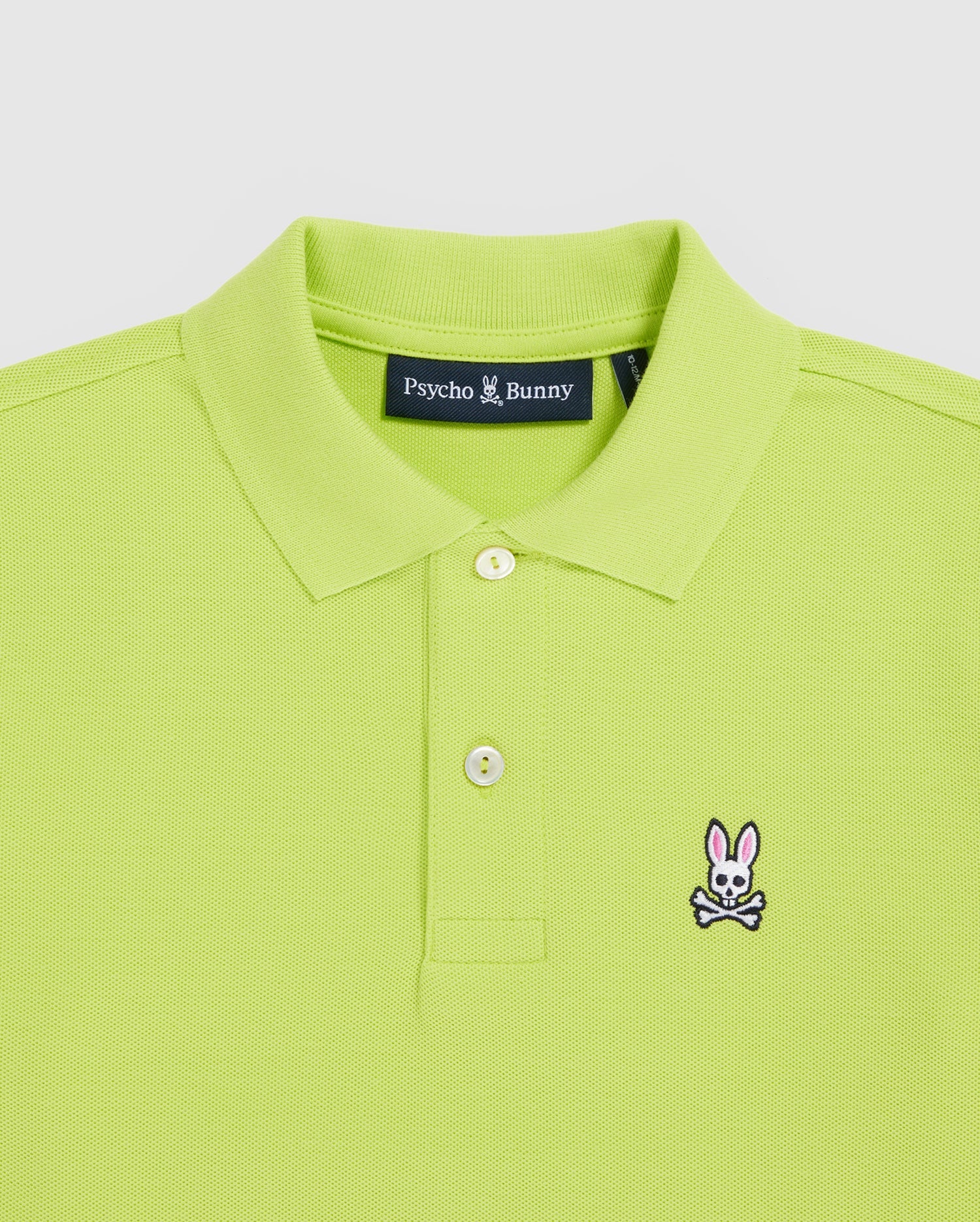 The Psycho Bunny Kids Classic Polo (B0K001CRPC) in lime green features a fold-over collar, two buttons, and a chest embroidery of a bunny with crossbones. Made from Pima cotton for quality, it offers a regular fit design.