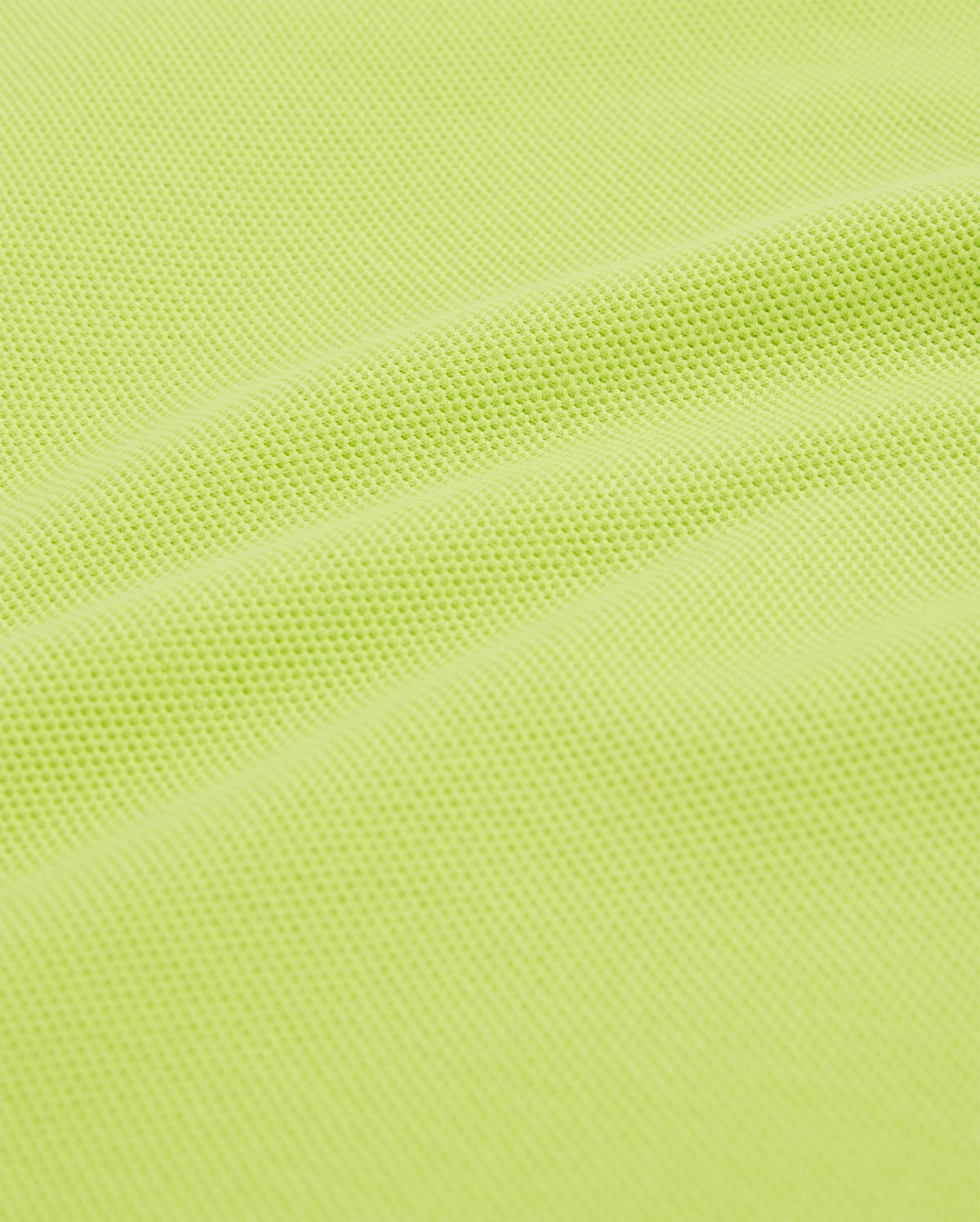 A close-up of the KIDS CLASSIC POLO - B0K001CRPC by Psycho Bunny shows a textured, lime green fabric with a subtle wave pattern, resembling classic piqué designs. Crafted from a breathable, slightly elastic mesh material like soft Pima cotton.