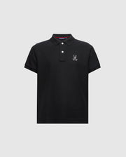 Introducing the KIDS ALEXANDER PIQUE POLO - B0K101E200 from Psycho Bunny. This fashionable black polo for kids features short sleeves and a buttoned collar, adorned with an embroidered logo showcasing a cartoon rabbit with crossed bones on the chest, elegantly set against a light gray background.