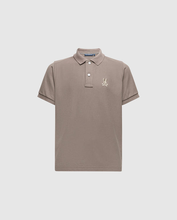 The KIDS ALEXANDER PIQUE POLO - B0K101E200 by Psycho Bunny is a chic children's polo shirt in a gentle beige color, made from high-quality Pima cotton. It includes a traditional collar and short sleeves, adorned with an understated embroidered palm tree logo on the left chest. Presented against a simple light grey background for a sophisticated appeal.
