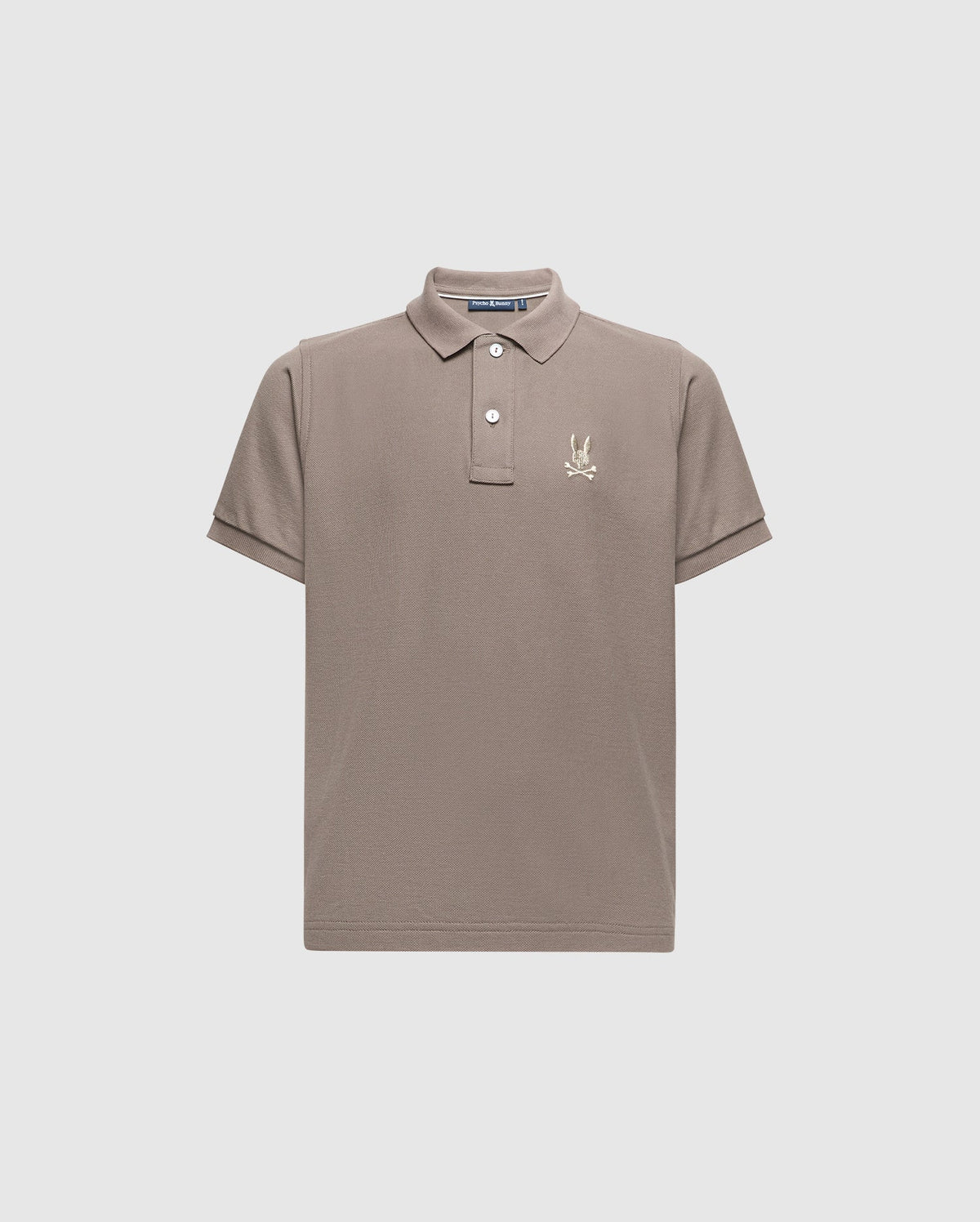 The KIDS ALEXANDER PIQUE POLO - B0K101E200 by Psycho Bunny is a chic children's polo shirt in a gentle beige color, made from high-quality Pima cotton. It includes a traditional collar and short sleeves, adorned with an understated embroidered palm tree logo on the left chest. Presented against a simple light grey background for a sophisticated appeal.