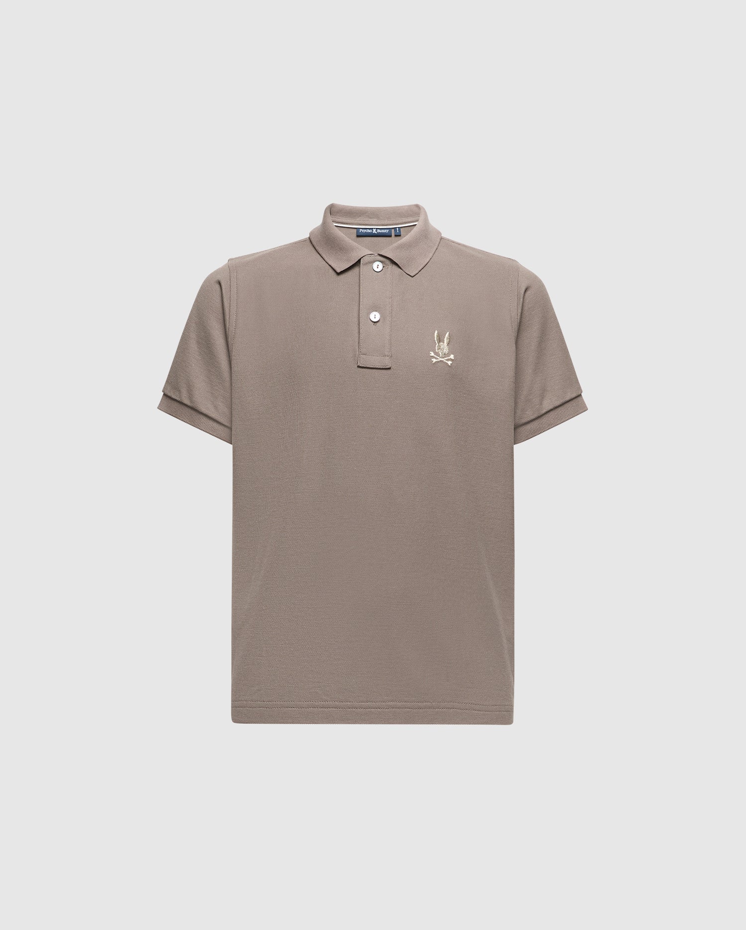 The KIDS ALEXANDER PIQUE POLO - B0K101E200 by Psycho Bunny is a chic children's polo shirt in a gentle beige color, made from high-quality Pima cotton. It includes a traditional collar and short sleeves, adorned with an understated embroidered palm tree logo on the left chest. Presented against a simple light grey background for a sophisticated appeal.