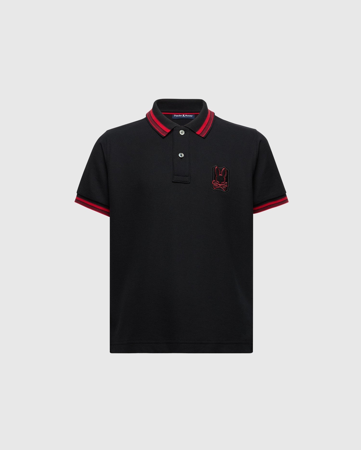The KIDS PIERCE PIQUE POLO - B0K201E200 by Psycho Bunny is made from premium Pima cotton and features a timeless design with short sleeves. It includes red trim on the collar and sleeve hems, buttons near the collar, and an embroidered red bunny logo on the left chest.