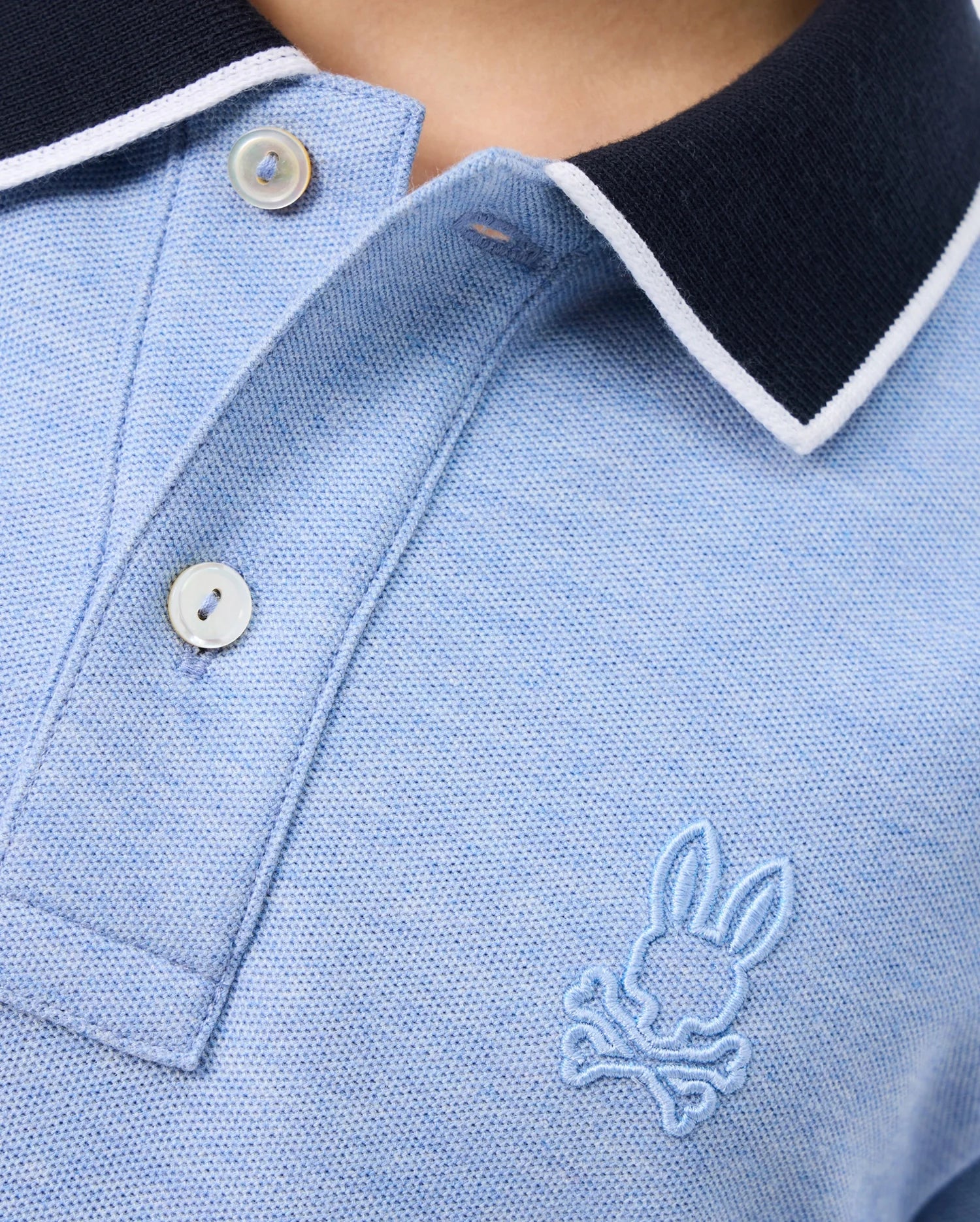 A close-up of a KIDS WINDCREST PIQUE POLO SHIRT - B0K592C200 by Psycho Bunny featuring a stylish striped collar.