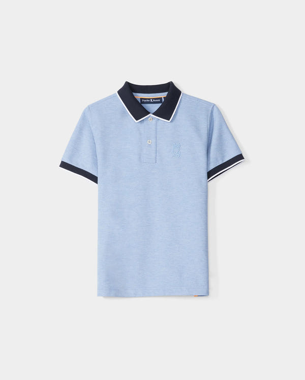 A KIDS WINDCREST PIQUE POLO SHIRT - B0K592C200 in light blue with a color blocked collar and sleeve trim. The dark blue collar features a white stripe on the edge, and the shirt has two buttons at the neckline. A raised-embroidered chest Bunny adorns the left chest area, set against a plain white background by Psycho Bunny.