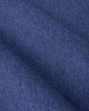 Close-up of a blue textile fabric with a fine weave. The image shows a soft texture and slight folding, highlighting the material's smooth and uniform surface, akin to that of the KIDS WINDCREST PIQUE POLO SHIRT - B0K592C200 by Psycho Bunny. The fabric has a consistent dark blue hue.