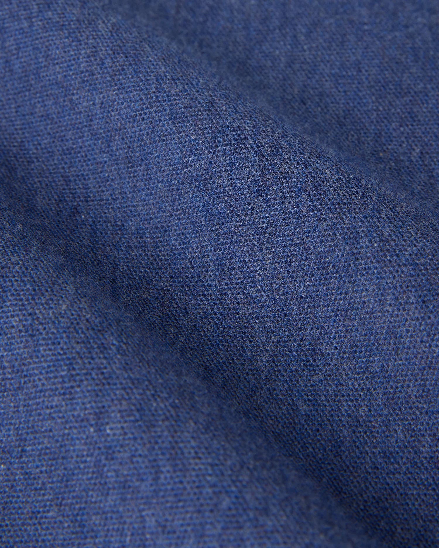 Close-up of a blue textile fabric with a fine weave. The image shows a soft texture and slight folding, highlighting the material's smooth and uniform surface, akin to that of the KIDS WINDCREST PIQUE POLO SHIRT - B0K592C200 by Psycho Bunny. The fabric has a consistent dark blue hue.