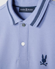A close-up of the KIDS RIVIERA PIQUE POLO SHIRT - B0K640C200 by Psycho Bunny in light blue Pima cotton piqué showcases a dark blue embroidered chest Bunny logo with a bunny and crossbones. The collar features a striped pattern, and the shirt comes with two buttons.