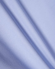Close-up of light blue textured fabric with a fine mesh pattern, similar to Pima cotton piqué. The material shows gentle diagonal folds, indicative of its soft drape and smooth surface, echoing the refined elegance characteristic of the Psycho Bunny KIDS RIVIERA PIQUE POLO SHIRT - B0K640C200.