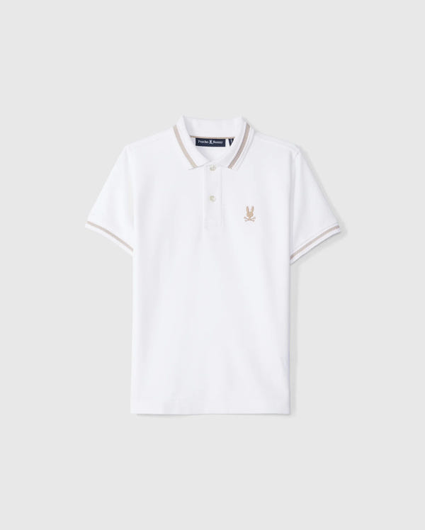 The Psycho Bunny KIDS RIVIERA PIQUE POLO SHIRT - B0K640C200 is a white short-sleeved polo shirt made from Pima cotton. It features a small embroidered Bunny logo on the left chest, a classic collar with a two-button placket, and contrasting beige trim on the collar and sleeve cuffs.