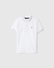 The Psycho Bunny KIDS RIVIERA PIQUE POLO SHIRT - B0K640C200 is a white short-sleeved polo shirt made from Pima cotton. It features a small embroidered Bunny logo on the left chest, a classic collar with a two-button placket, and contrasting beige trim on the collar and sleeve cuffs.