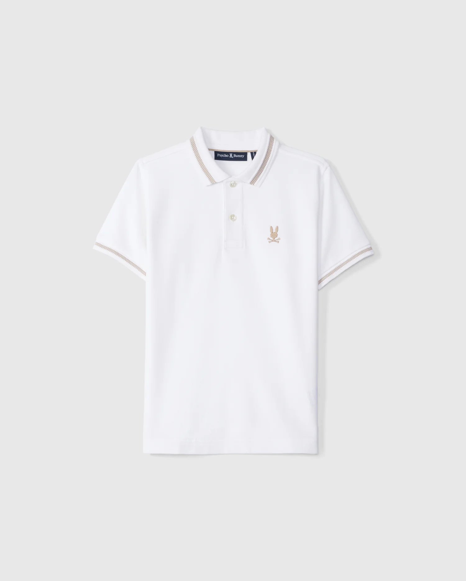 The Psycho Bunny KIDS RIVIERA PIQUE POLO SHIRT - B0K640C200 is a white short-sleeved polo shirt made from Pima cotton. It features a small embroidered Bunny logo on the left chest, a classic collar with a two-button placket, and contrasting beige trim on the collar and sleeve cuffs.