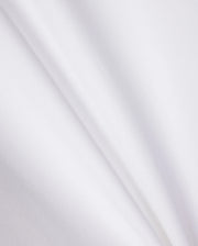 A close-up of a smooth, white Pima cotton fabric with subtle, diagonal creases. The texture appears soft and light, showcasing the clean and pristine appearance of the KIDS RIVIERA PIQUE POLO SHIRT - B0K640C200 by Psycho Bunny, reminiscent of a refined Riviera polo.