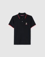 The KIDS KAYDEN PIQUE POLO - B0K675C200 by Psycho Bunny is a black polo shirt accented with red trim on the collar and sleeve cuffs. It has a small, white, embroidered rabbit logo on the left chest. Crafted from Pima cotton piqué, this shirt features a two-button placket and is showcased against a plain white background.