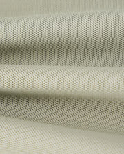 Close-up of a piece of light gray, finely textured Pima cotton pique fabric from the Psycho Bunny KIDS KAYDEN PIQUE POLO - B0K675C200, with a slightly rough surface. The fabric appears to be folded, creating gentle, undulating waves. The material's weave is visible, featuring a uniform pattern of small, evenly spaced dots.