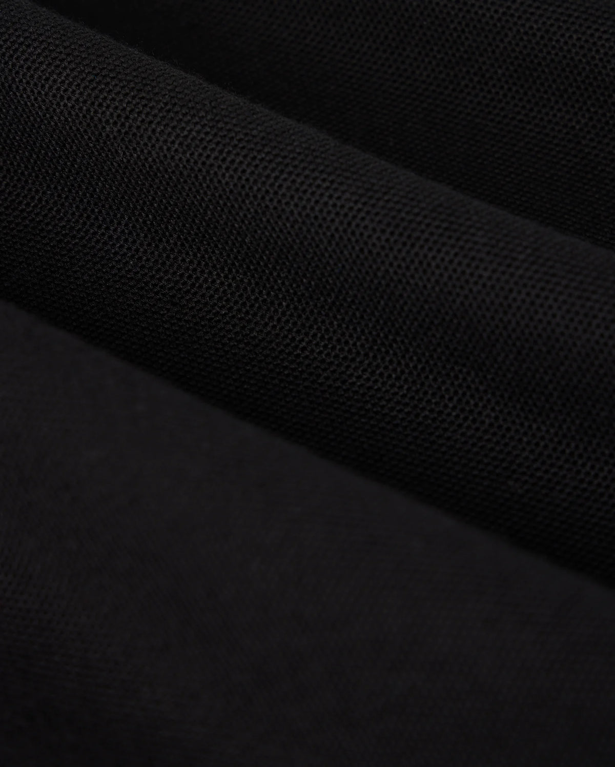Close-up image of a piece of black fabric, reminiscent of the luxurious texture found in a Psycho Bunny KIDS MALTON PIQUE POLO SHIRT (B0K950D200). The material appears textured and has a matte finish, with subtle shading indicating folds and gentle waves.