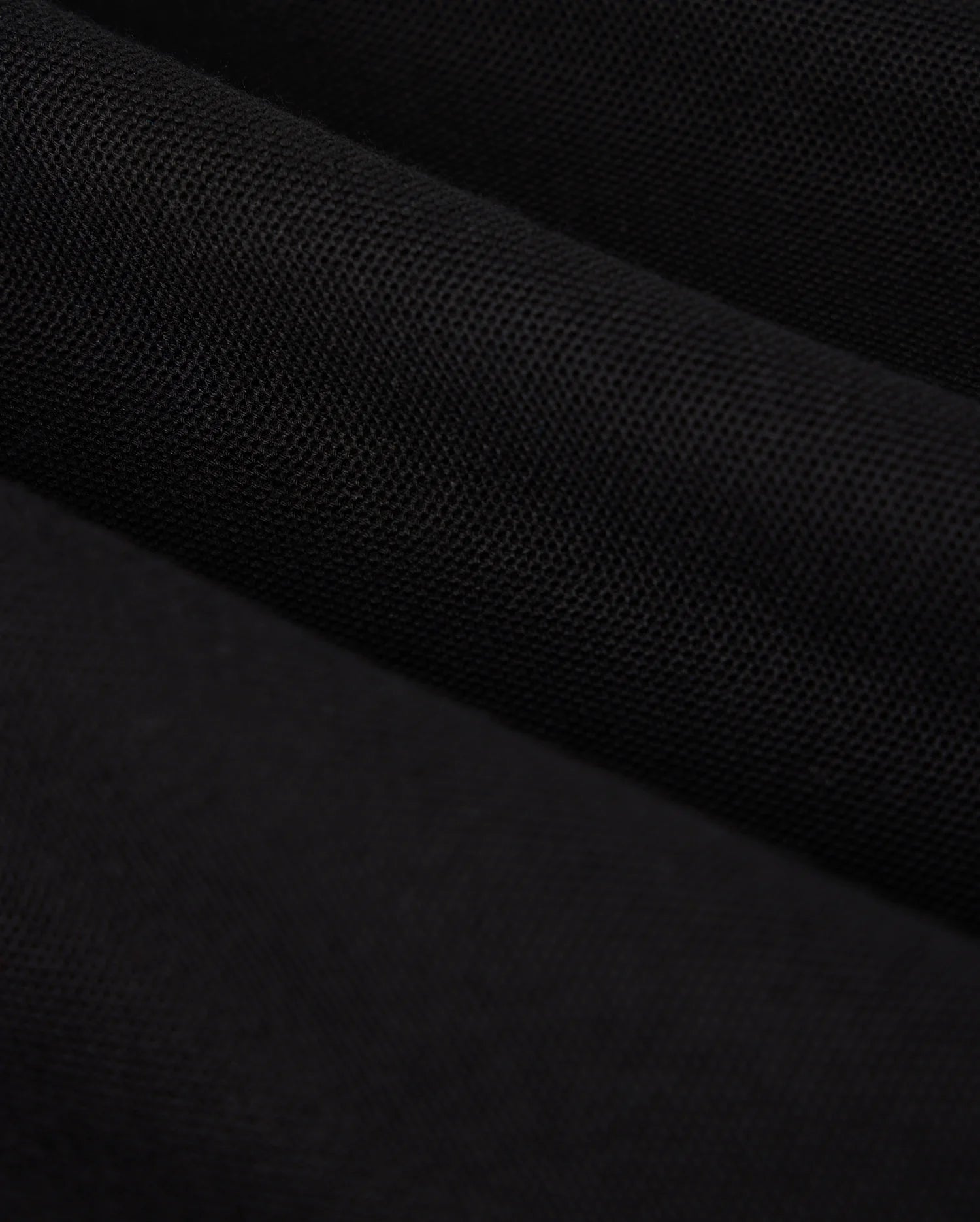 Close-up image of a piece of black fabric, reminiscent of the luxurious texture found in a Psycho Bunny KIDS MALTON PIQUE POLO SHIRT (B0K950D200). The material appears textured and has a matte finish, with subtle shading indicating folds and gentle waves.