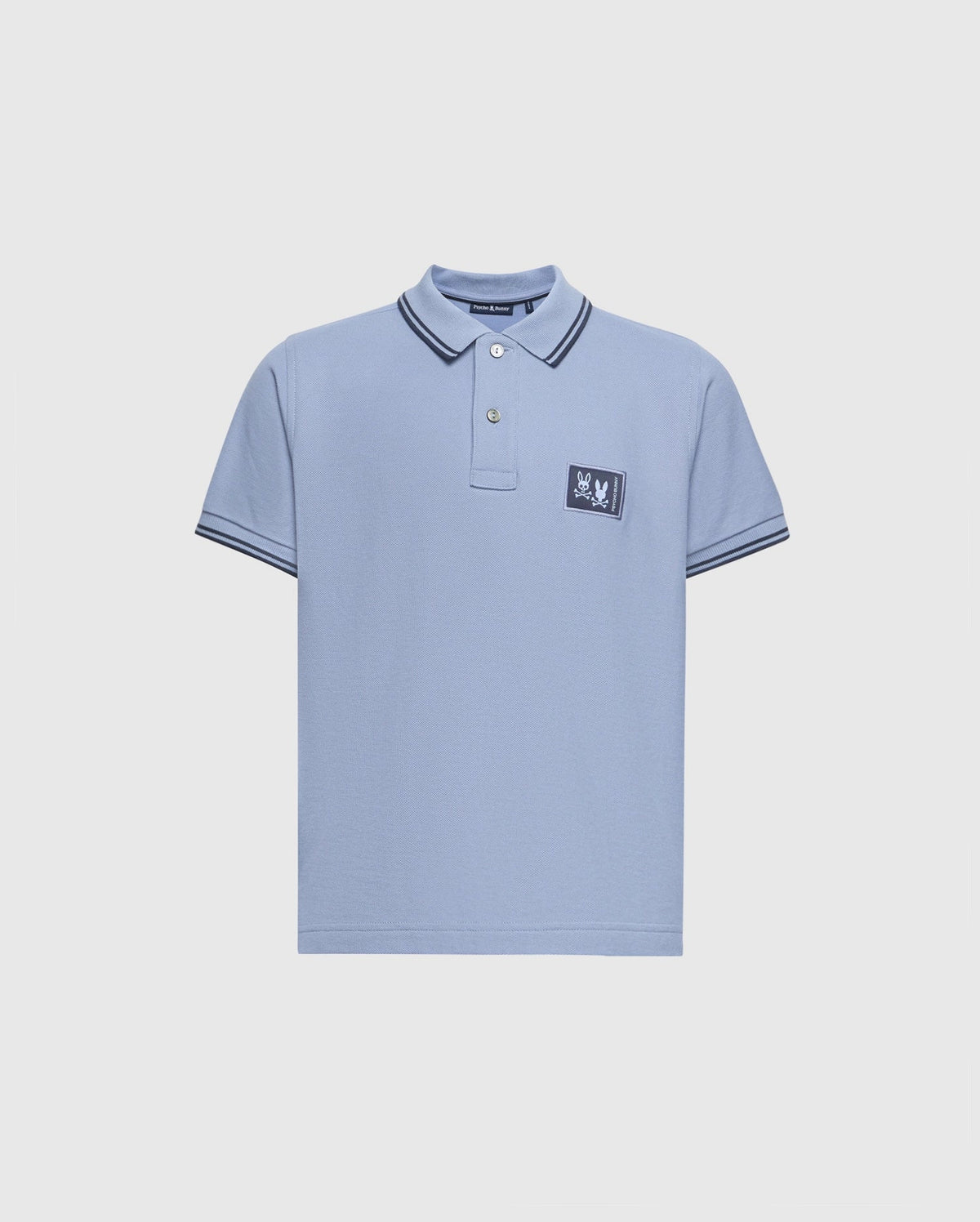 The Psycho Bunny Kids Monroe Pique Polo (B0K964D200) is a regular fit light blue shirt featuring short sleeves, a collar with double black stripes, and a small rectangular patch on the left chest with the brand's appliqué logo.