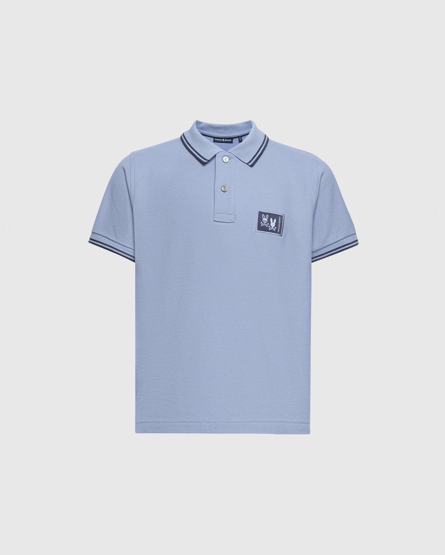 The Psycho Bunny Kids Monroe Pique Polo (B0K964D200) is a regular fit light blue shirt featuring short sleeves, a collar with double black stripes, and a small rectangular patch on the left chest with the brand's appliqué logo.