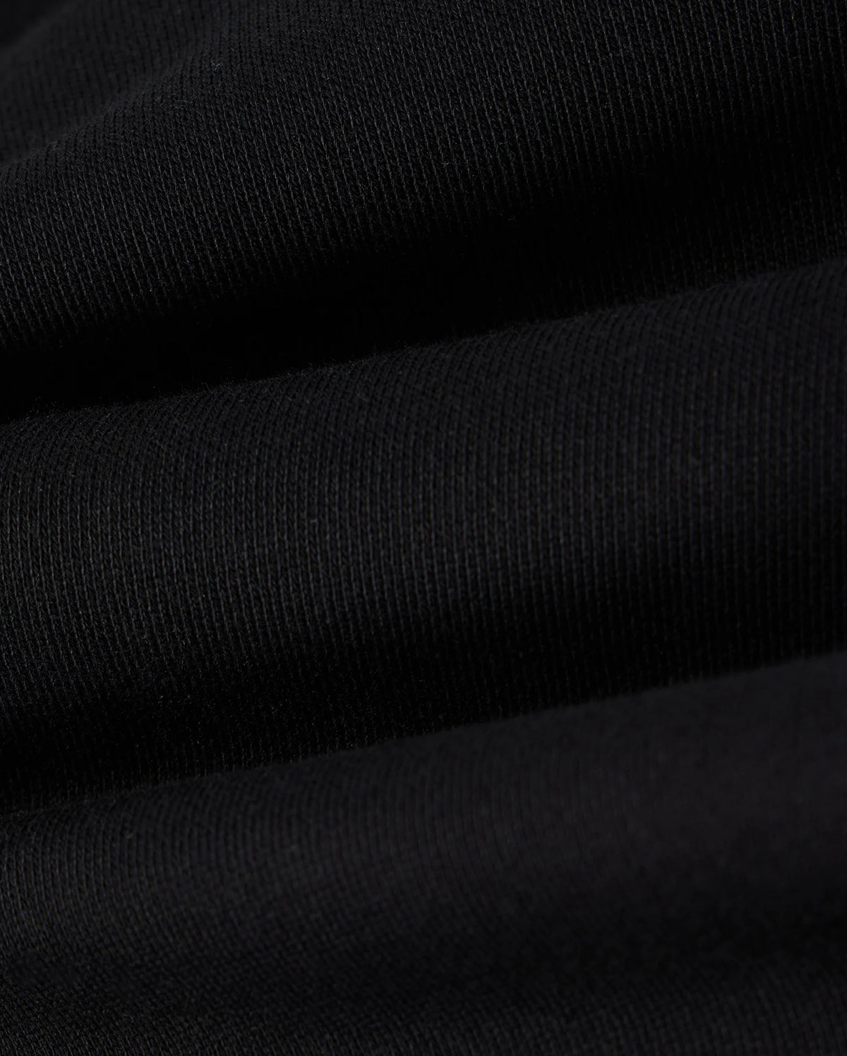 Close-up view of the black cotton fleece fabric with visible ribbing and slight texture, creating a series of gentle horizontal waves, perfect for the Psycho Bunny KIDS LENOX REGULAR FIT SWEATPANT.