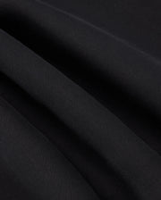 Close-up image of the black fabric with fine, parallel ribbing showcasing its texture. The fabric exhibits slight waves due to gentle folds, reminiscent of the subtle detail found in the high-quality KIDS TRAVIS TRACK PANT - B0P143D200 by Psycho Bunny, which is both elastic and comfortable.
