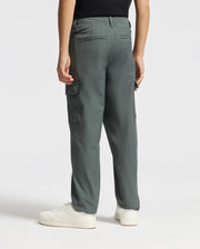 A person wearing the KIDS GREEN VALLEY CARGO PANT - B0P199E200 in a vibrant green stands with their back to the camera, paired with crisp white sneakers. These stylish cargo pants from Psycho Bunny feature side pockets and an elastic waistband. The ensemble is completed with a black top.