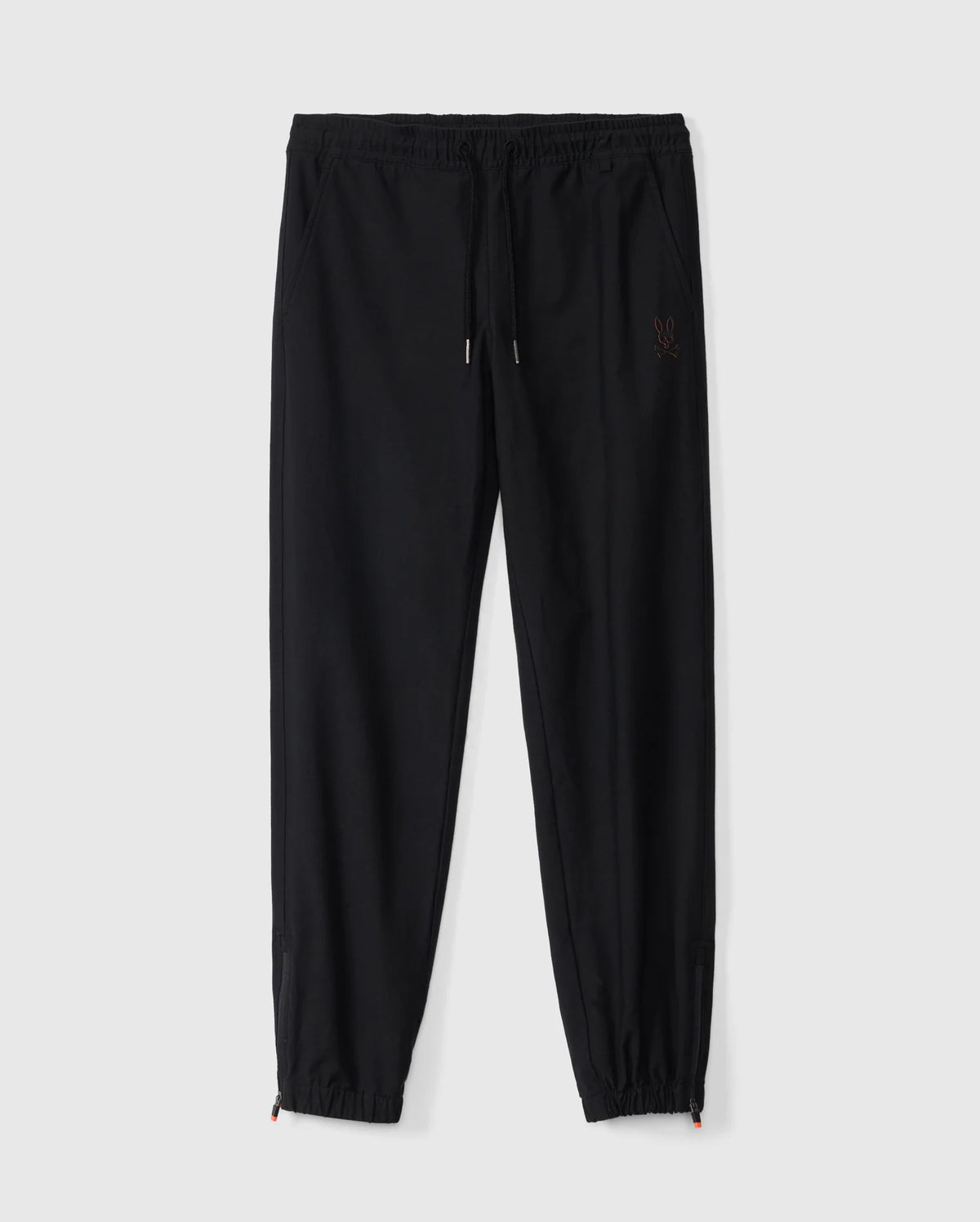A pair of Psycho Bunny Kids Madison Commuter Pants (B0P395Z1WB) in black, featuring elastic cuffs, a drawstring waistband, and a small embroidered logo on the left thigh. These joggers offer a relaxed fit and include zippered expansion vents, displayed against a plain white background.