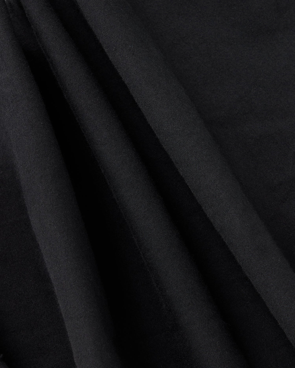 Close-up of draped black fabric with smooth texture and soft folds. The fabric is captured in a way that highlights its rich, deep color and fine, subtle weave, reminiscent of the elegance of the Psycho Bunny Kids Madison Commuter Pant - B0P395Z1WB—an appearance both sophisticated and timeless.