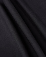 Close-up of black fabric with light reflecting off its smooth surface, creating subtle lines and textures. The material, perfect for the KIDS WALTER LIGHTWEIGHT SWEATPANT - B0P860D200 by Psycho Bunny, appears slightly folded or draped, showcasing its softness and sheen ideal for casual wear.