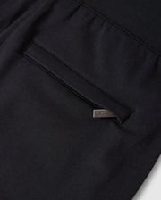 Close-up of a Psycho Bunny KIDS WALTER LIGHTWEIGHT SWEATPANT - B0P860D200 in black, featuring a pocket with a vertical opening and a silver metal tag attached to the edge. The fabric appears dense yet breathable, with neat and precise stitching that makes it perfect for casual wear.