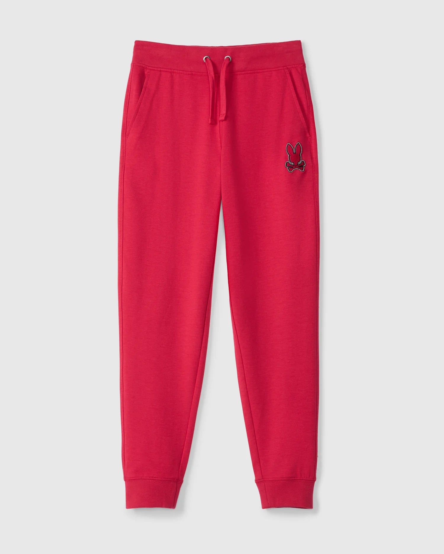 The KIDS WALTER LIGHTWEIGHT SWEATPANT - B0P860D200 by Psycho Bunny is showcased against a white background. These vibrant red sweatpants boast an elastic waistband with a drawstring, side pockets, and elastic cuffs at the ankles. The left thigh features an embroidered logo in black and white. Ideal for casual wear, they offer a breathable fit.
