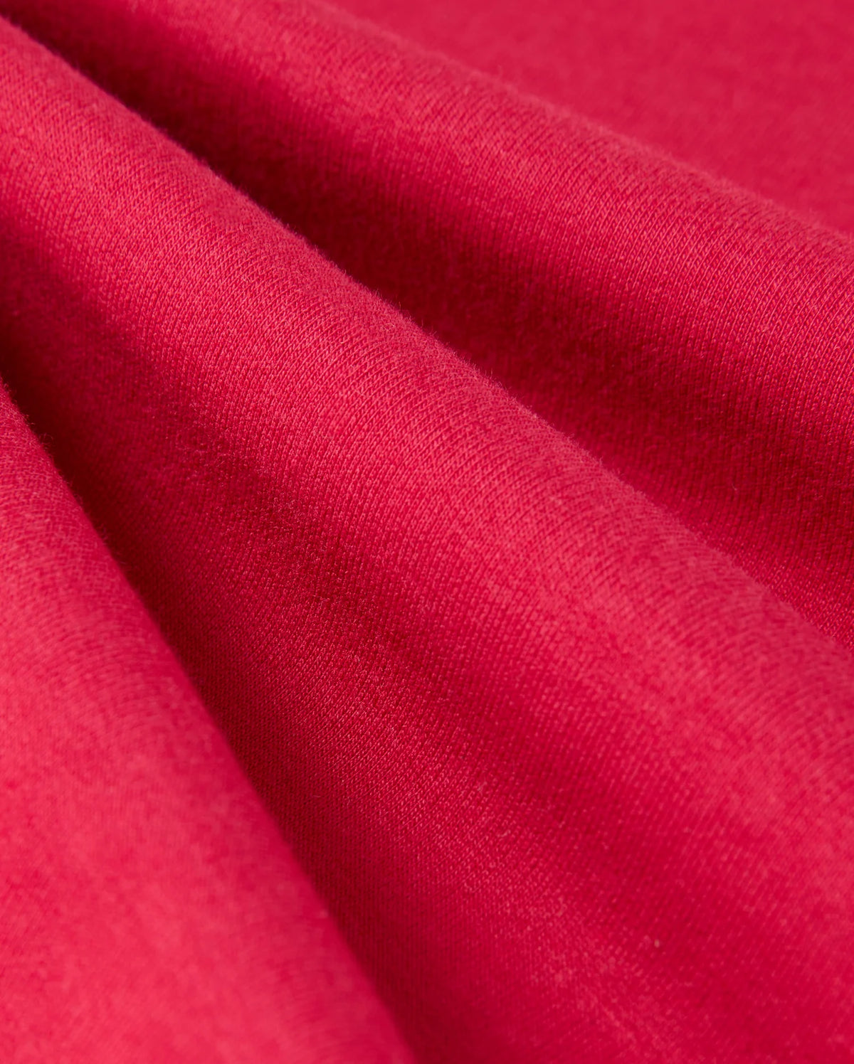 Close-up of the red fabric in the KIDS WALTER LIGHTWEIGHT SWEATPANT - B0P860D200 by Psycho Bunny. The texture appears soft and smooth, with even, consistent coloration. The fabric catches light subtly, highlighting its fine weave and slight sheen—perfect for a breathable fit in casual wear or lightweight sweatpants.