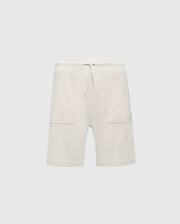 The KIDS TAYLOR LIGHT PIQUE SWEATSHORT by Psycho Bunny features white fleece with an adjustable drawstring, two large front pockets, and soft Pima cotton for comfort. A playful embroidered Bunny stands out against the light gray background, perfect for casual-chic style.