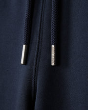Close-up of dark blue fabric sweatshorts with navy drawstrings featuring "Psycho Bunny" engraved metal tips. This naturally breathable fleece from Psycho Bunny's KIDS LENOX SWEATSHORT - B0R377B200 collection is perfect for an active lifestyle.