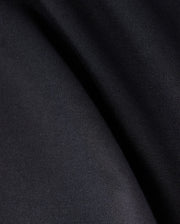 Close-up of a smooth, dark fabric with soft folds, displaying a gradient of black and dark gray shades. The texture appears uniform and slightly matte, creating subtle shadows and highlights across the surface. This Micro French Terry fabric promises both comfort and style in every Psycho Bunny KIDS LIVINGSTON TERRY SWEATSHORT - B0R408B200 design.
