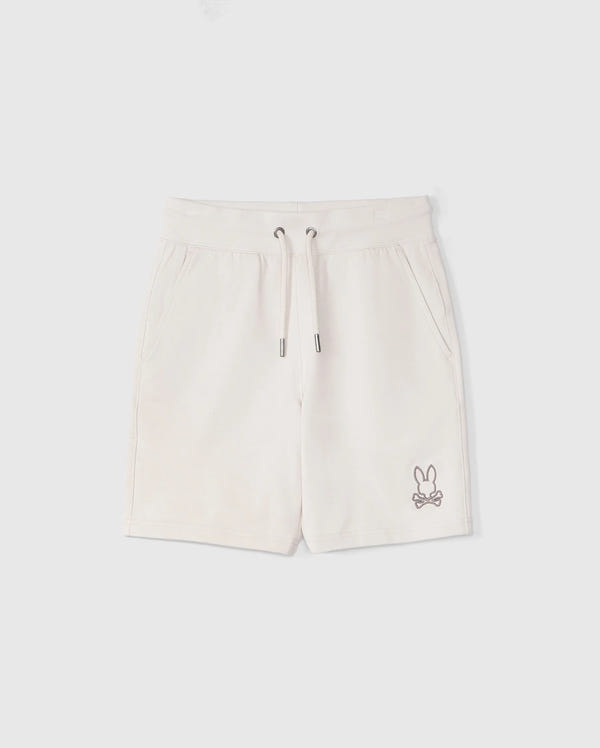 A pair of light beige KIDS LIVINGSTON TERRY SWEATSHORT shorts from Psycho Bunny with a drawstring waist and side pockets, featuring a small embroidered bunny logo on the bottom left leg, displayed on a plain white background.