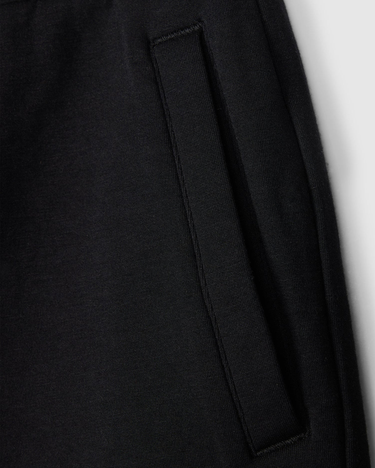 Close-up of a black cotton blend fleece texture showing details of a stitched pocket on a Psycho Bunny KIDS LYONS SWEATSHORT - B0R578C200.