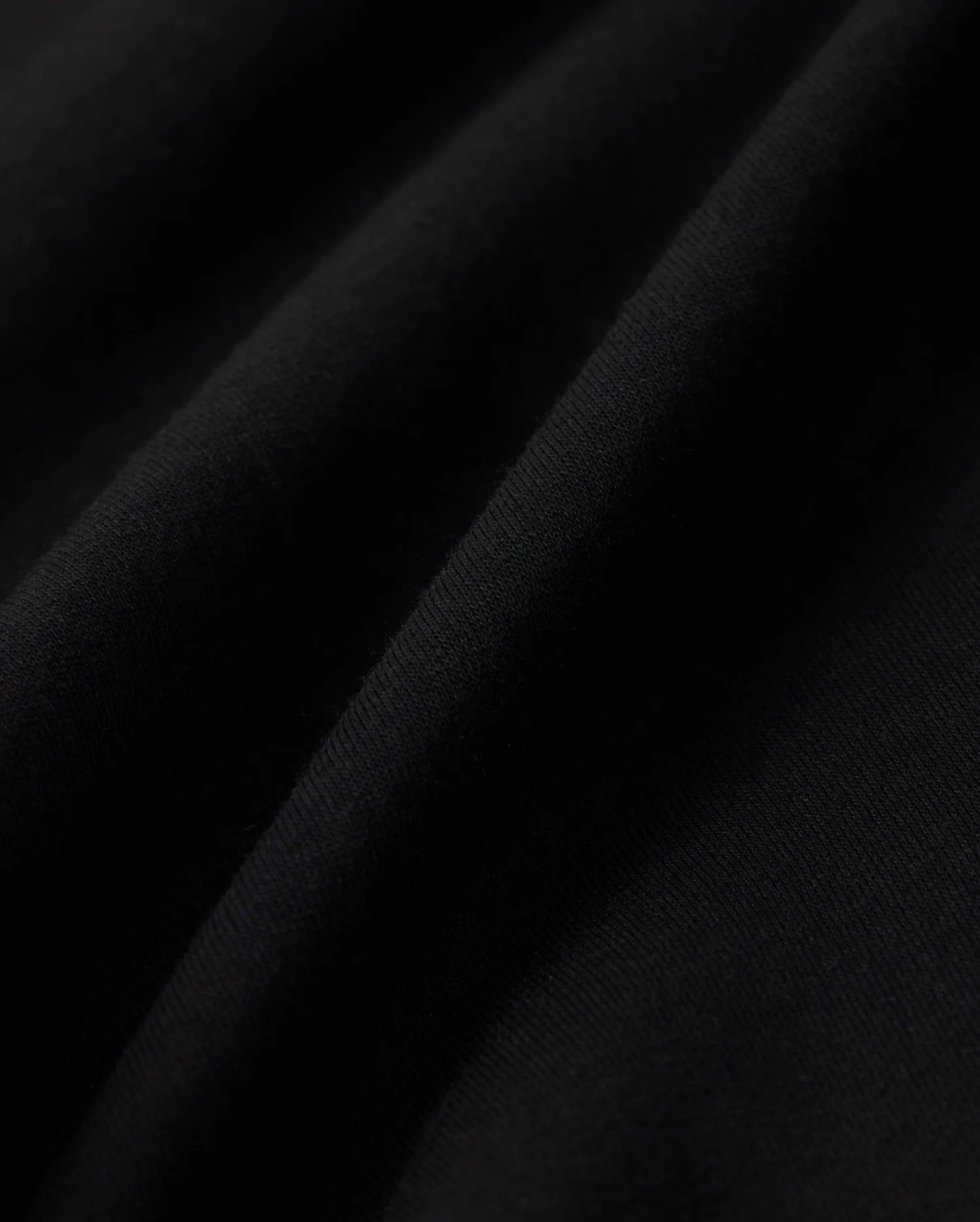 Close-up of black cotton blend fleece fabric with visible texture and soft folds. Light creates subtle highlights and shadows, emphasizing the Psycho Bunny KIDS LYONS SWEATSHORT - B0R578C200's fine details and quality.