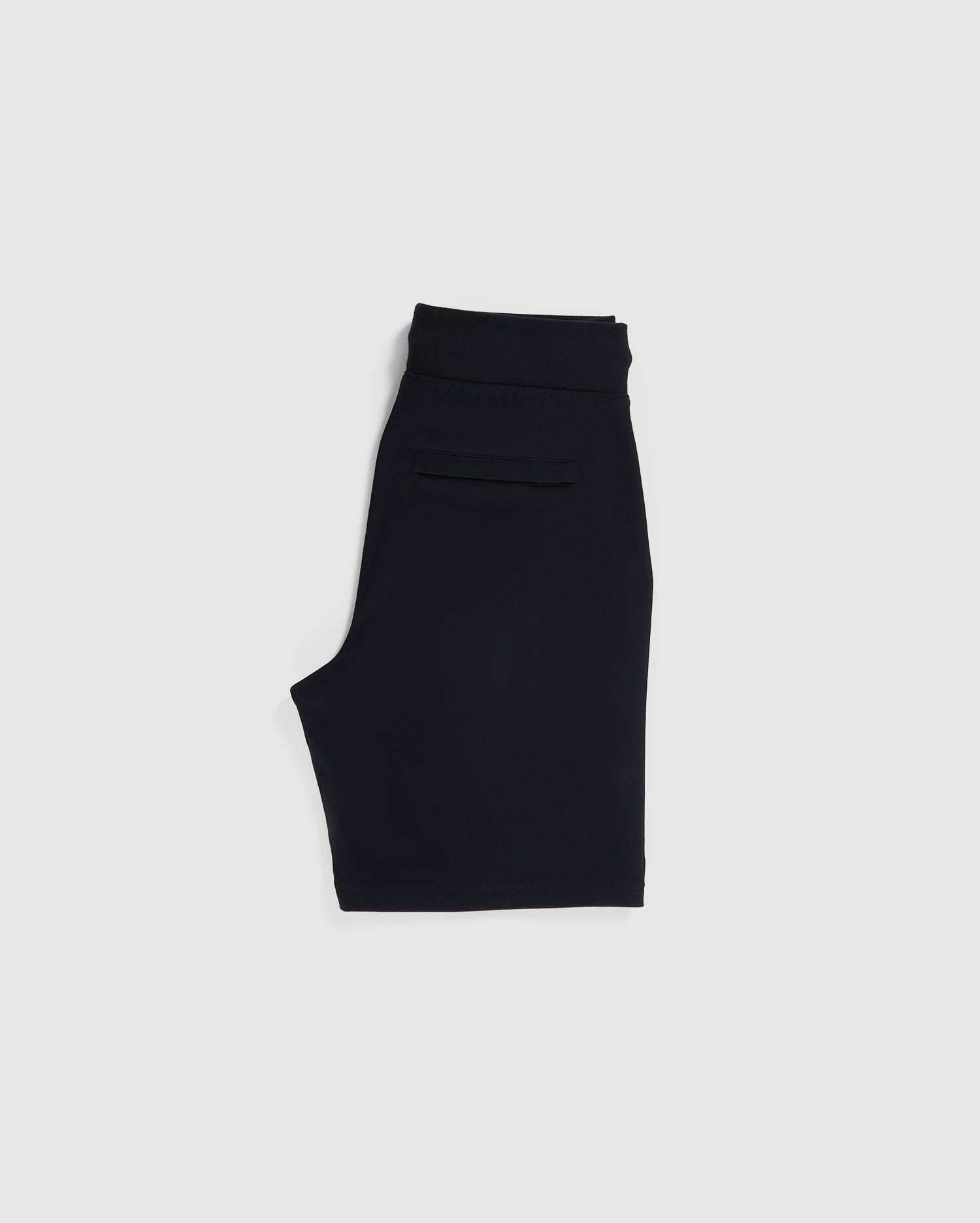 Black knee-length French terry shorts with an elastic waistband, featuring a sleek, minimalist design. These Psycho Bunny KIDS CLASSIC FRENCH TERRY SHORTS - B0R829ARFT have a single back pocket and are presented against a plain, light grey background.