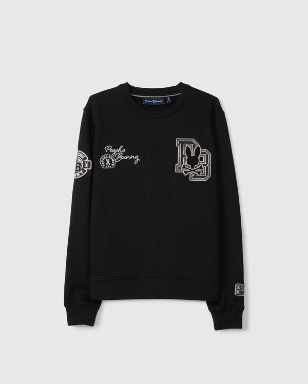 The KIDS ZACK VARSITY SWEATSHIRT by Psycho Bunny features chenille embroidery with a stylized letter “D” containing a rabbit, "Punk Bunny," and various decorative patches on the chest and sleeves. Its vintage-inspired logo is highlighted against the plain gray background of this black varsity sweatshirt.
