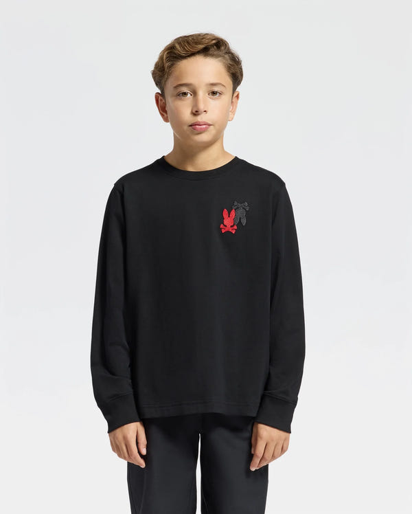 A young boy wearing the Psycho Bunny KIDS PIERCE LONG SLEEVE BACK GRAPHIC TEE - B0T178E200 with an embroidered bunny design is posed against a plain white background. He has short, light brown hair and gazes directly at the camera, proudly displaying the stylish red and black logo on his chest.