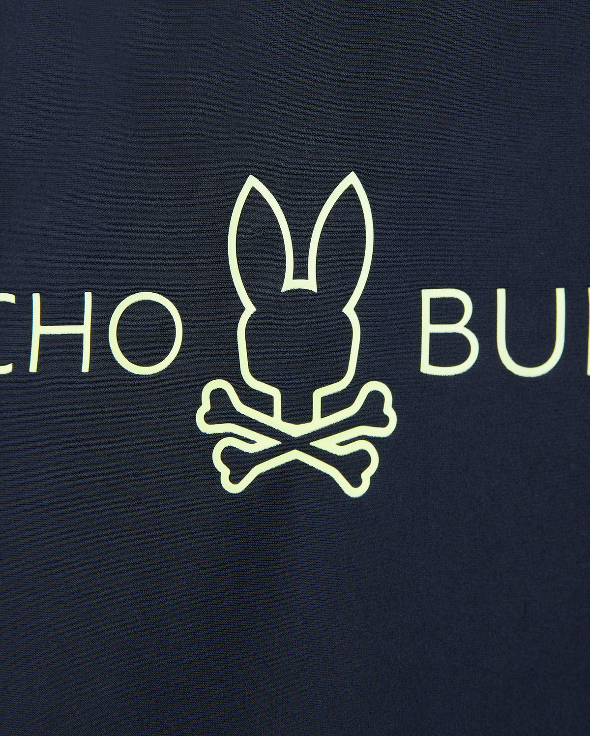 A yellow bunny head outline above crossed bones on a dark background offers quick-drying comfort. Partial letters "CHO" and "BU" are visible on this UPF 50+ Kids Long Sleeve Rash Guard from Psycho Bunny.