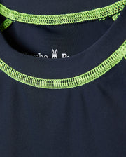 Close-up of a dark blue Psycho Bunny kids' long sleeve rash guard - B0T557C200, showcasing bright green neckline stitching and a small rabbit graphic inside the collar. It features quick-drying fabric and UPF 50+ protection for style and functionality.