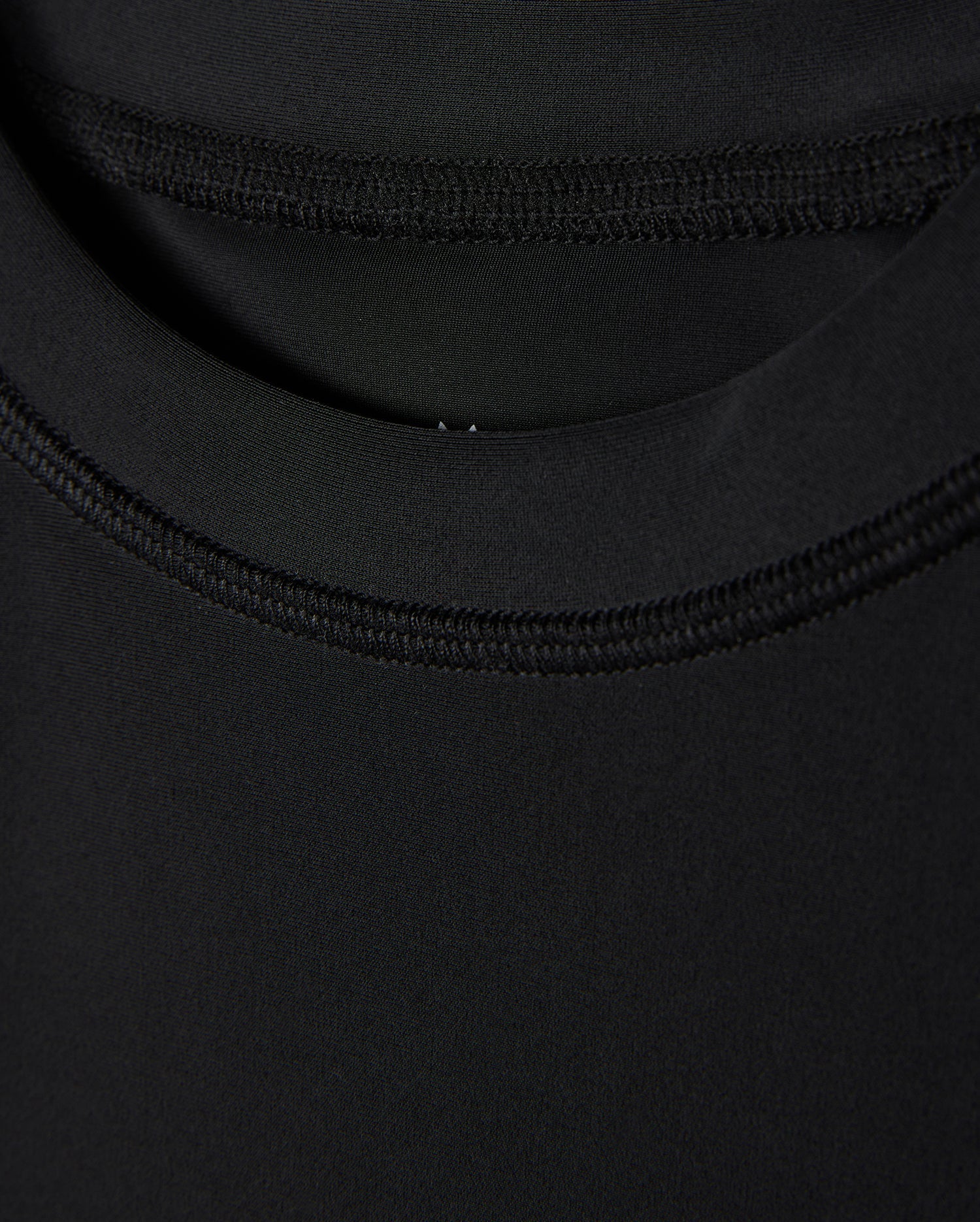Close-up of a black fabric texture showing detailed stitching and overlapping layers, focusing on the craftsmanship and UPF 50+ protection quality in the Psycho Bunny KIDS SAN LEON ANTI-UV RASHGUARD - B0T645C200.