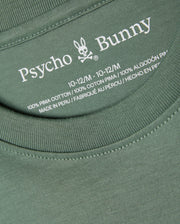 Close-up of the KIDS ALBERTON LONG SLEEVE TEE - B0T867D200 in green, featuring the label with the brand name "Psycho Bunny" and its signature bunny logo. Made from 100% Pima cotton and crafted in Peru, this versatile layering piece comes in size 10-12/M.