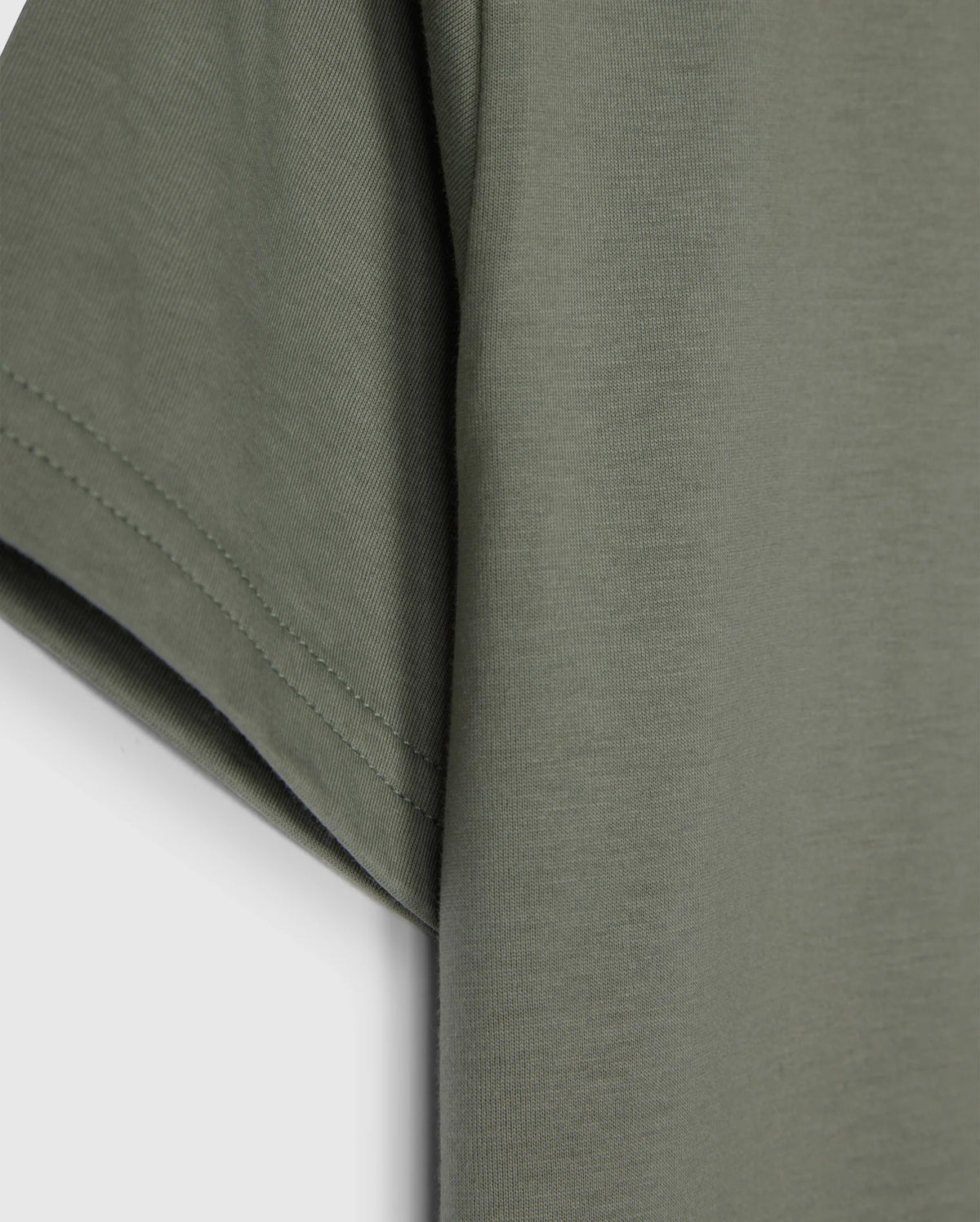 Close-up of the sleeve and side of an olive green Psycho Bunny KIDS CLASSIC CREW NECK TEE - B0U014B200 made from 100% Pima cotton against a white background. The fabric appears soft, with visible stitching along the hem of the sleeve. This kids' classic crew neck tee is perfect for back-to-school outfits.