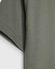 Close-up of the sleeve and side of an olive green Psycho Bunny KIDS CLASSIC CREW NECK TEE - B0U014B200 made from 100% Pima cotton against a white background. The fabric appears soft, with visible stitching along the hem of the sleeve. This kids' classic crew neck tee is perfect for back-to-school outfits.