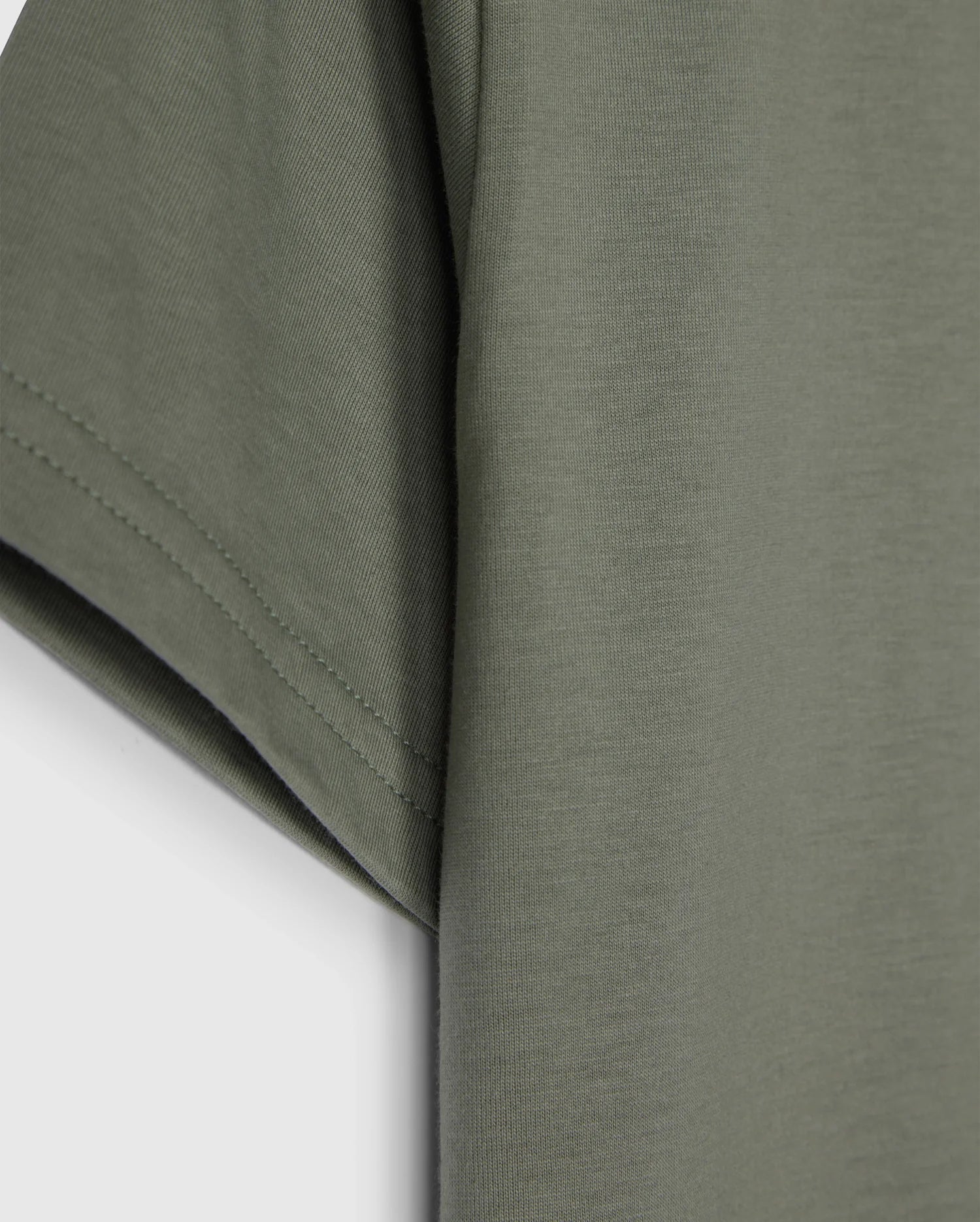 Close-up of the sleeve and side of an olive green Psycho Bunny KIDS CLASSIC CREW NECK TEE - B0U014B200 made from 100% Pima cotton against a white background. The fabric appears soft, with visible stitching along the hem of the sleeve. This kids' classic crew neck tee is perfect for back-to-school outfits.