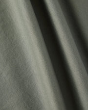 Close-up image of a green fabric showcasing its soft texture and weaving pattern. Made from 100% Pima cotton, the material is perfect for Psycho Bunny's Kids Classic Crew Neck Tee (B0U014B200). Light and shadows create subtle variations in the fabric's color.