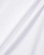 A close-up of the KIDS EMBROIDERED CLASSIC TEE - B0U020AR00 by Psycho Bunny, made from smooth Peruvian Pima cotton. The plain white fabric features subtle diagonal folds that are highlighted by gentle shadows in the lighting, showcasing its soft and clean surface. This texture is perfect for a classic tee or an embroidered chest Bunny design.